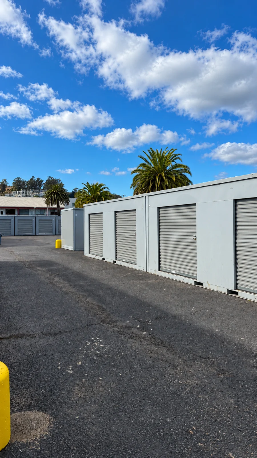 Row of storage units with metal roll-up doors beside the paved access area in Sausalito