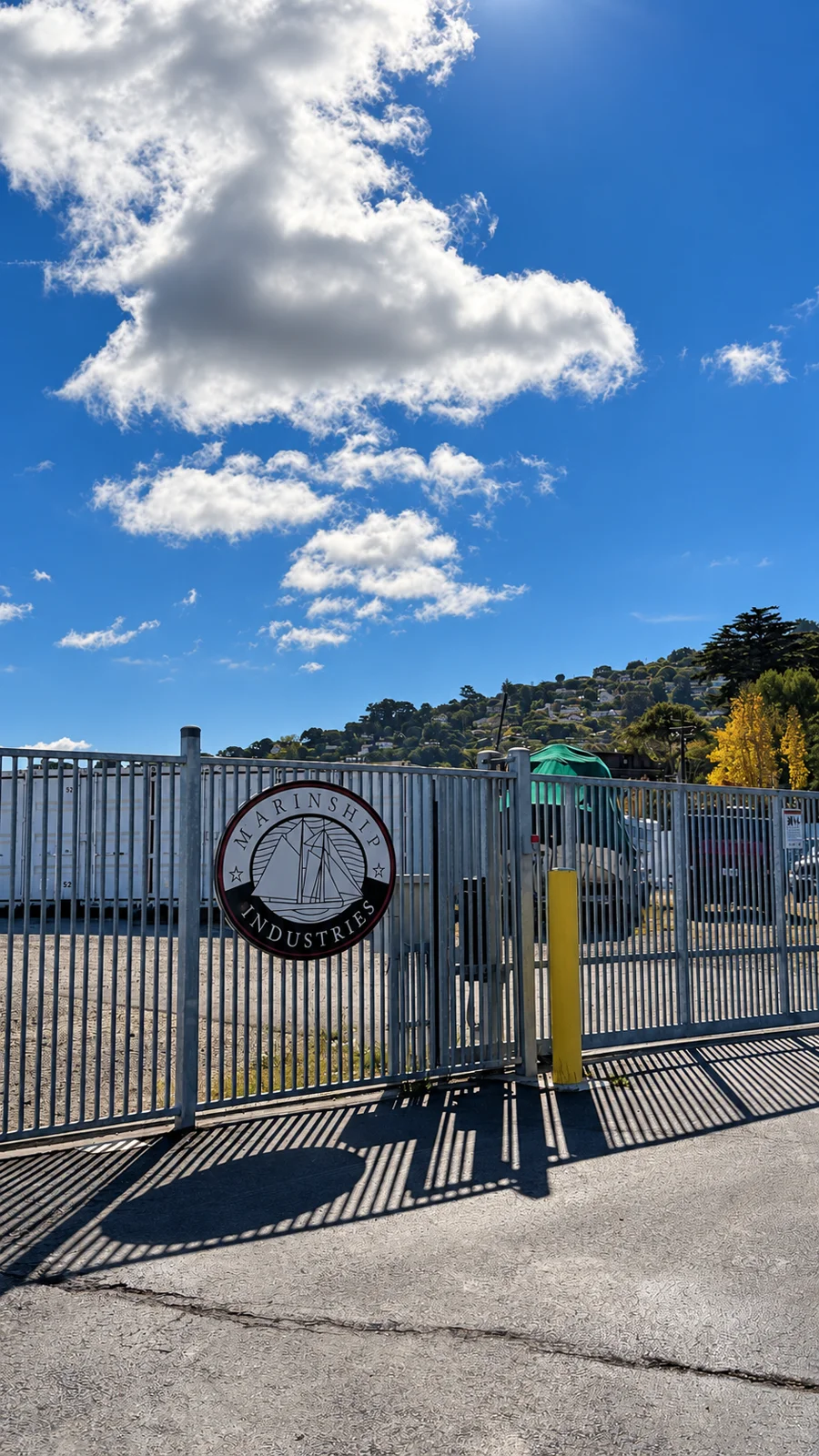 Marinship Industries entrance gate and circular sailboat sign beside the storage yard